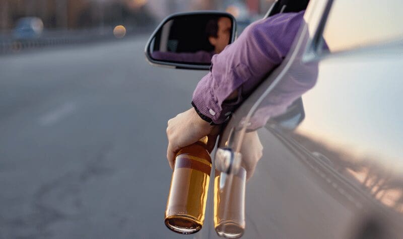 A driver who appears to be drinking a bottle of alcohol while driving